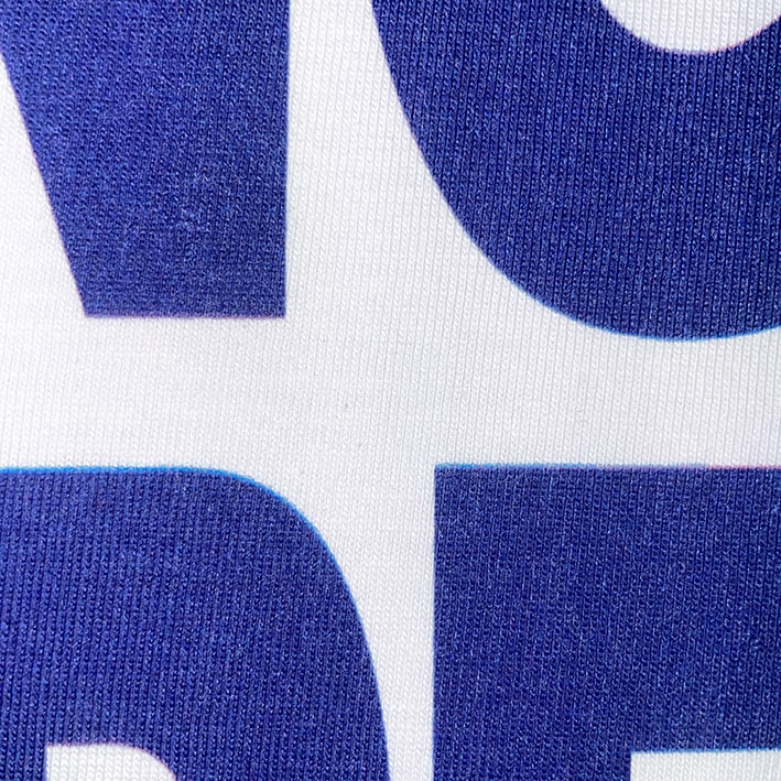 CALMECS T-SHIRT IN COLOR WHITE WITH BLUE MAKING THINGS HAPPEN FONT FRONT PRINT. CLOSE UP CALMECS LETTERS.