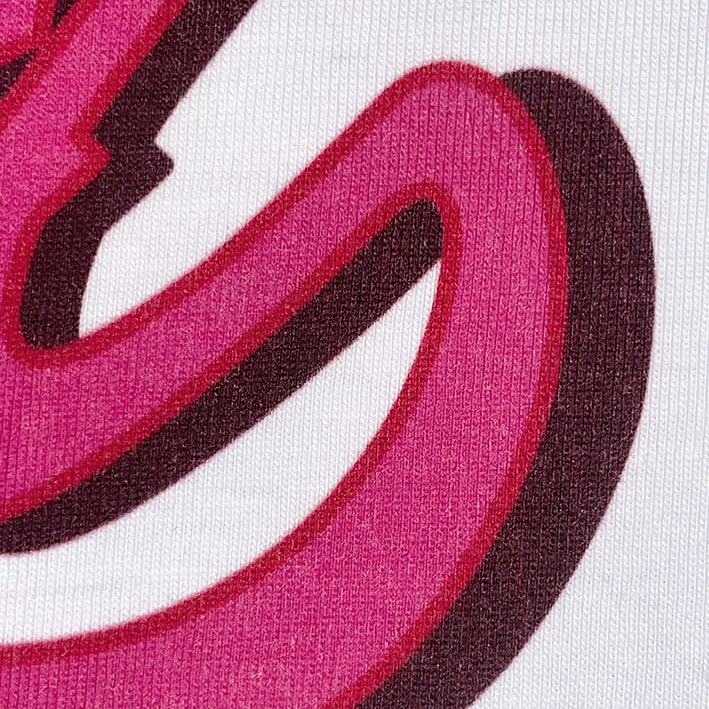 CALMECS T-SHIRT IN COLOR WHITE WITH PINK FONT FRONT PRINT. CLOSE UP LETTER.