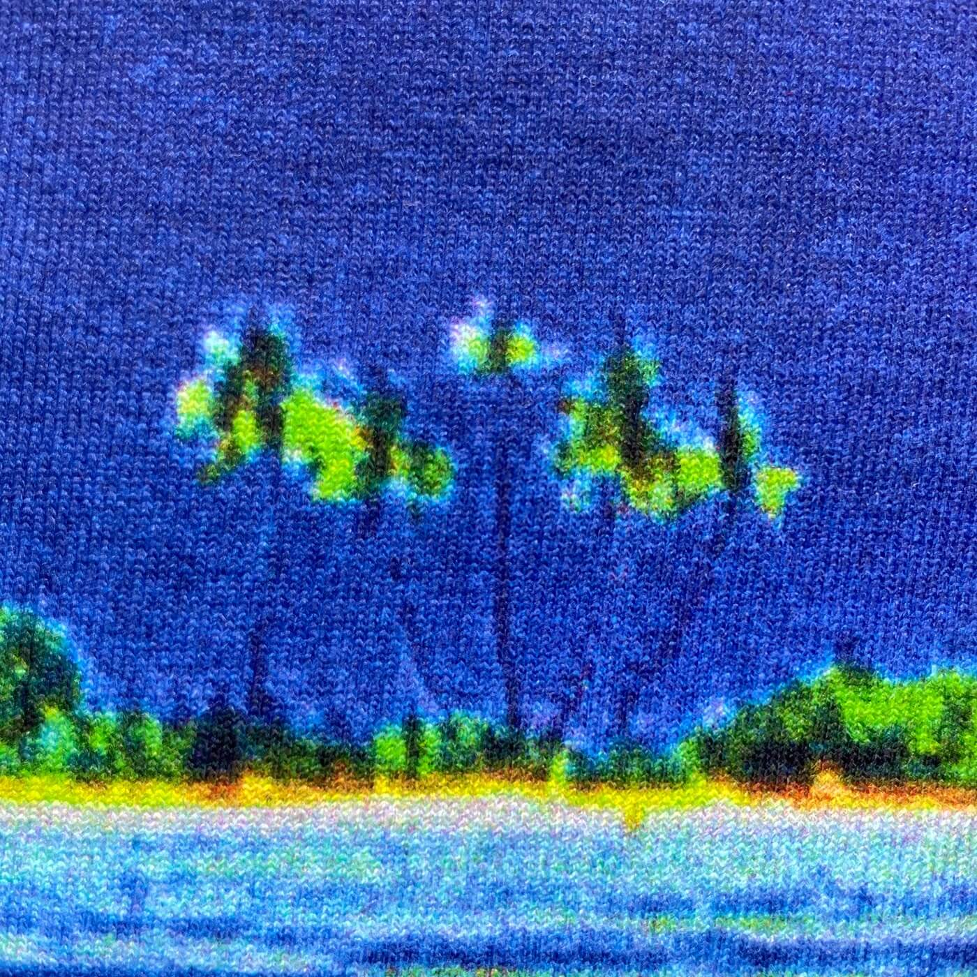 CALMECS T-SHIRT IN COLOR WHITE WITH TROPICAL ISLAND BACK PRINT. CLOSE-UP  PALM TREES AND BLUE SKY.