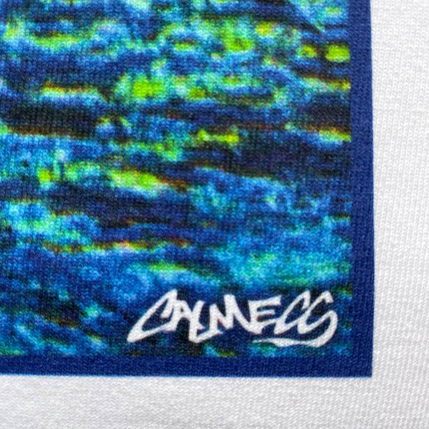 CALMECS T-SHIRT IN COLOR WHITE WITH TROPICAL ISLAND BACK PRINT. CLOSE-UP  CALMECS LOGO FONT.