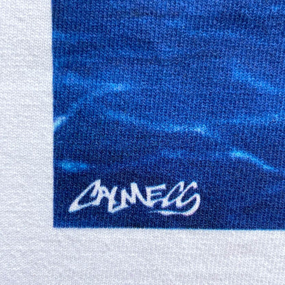 CALMECS T-SHIRT IN COLOR WHITE WITH RED COWBOY ON HORSE BACK PRINT. CLOSE UP CALMECS FONT.