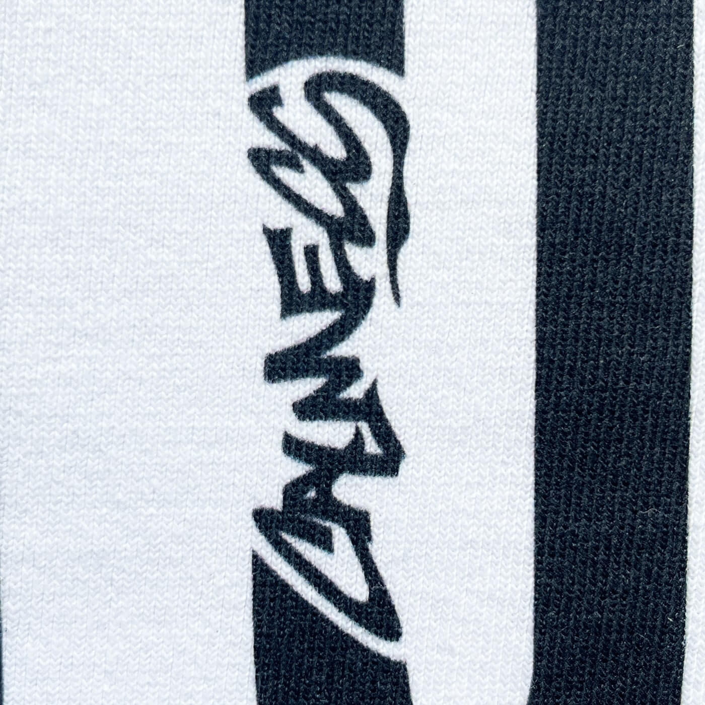 CALMECS T-SHIRT IN COLOR WHITE WITH BLACK DELUSIONAL FONT FRONT PRINT. CLOSE UP CALMECS FONT.