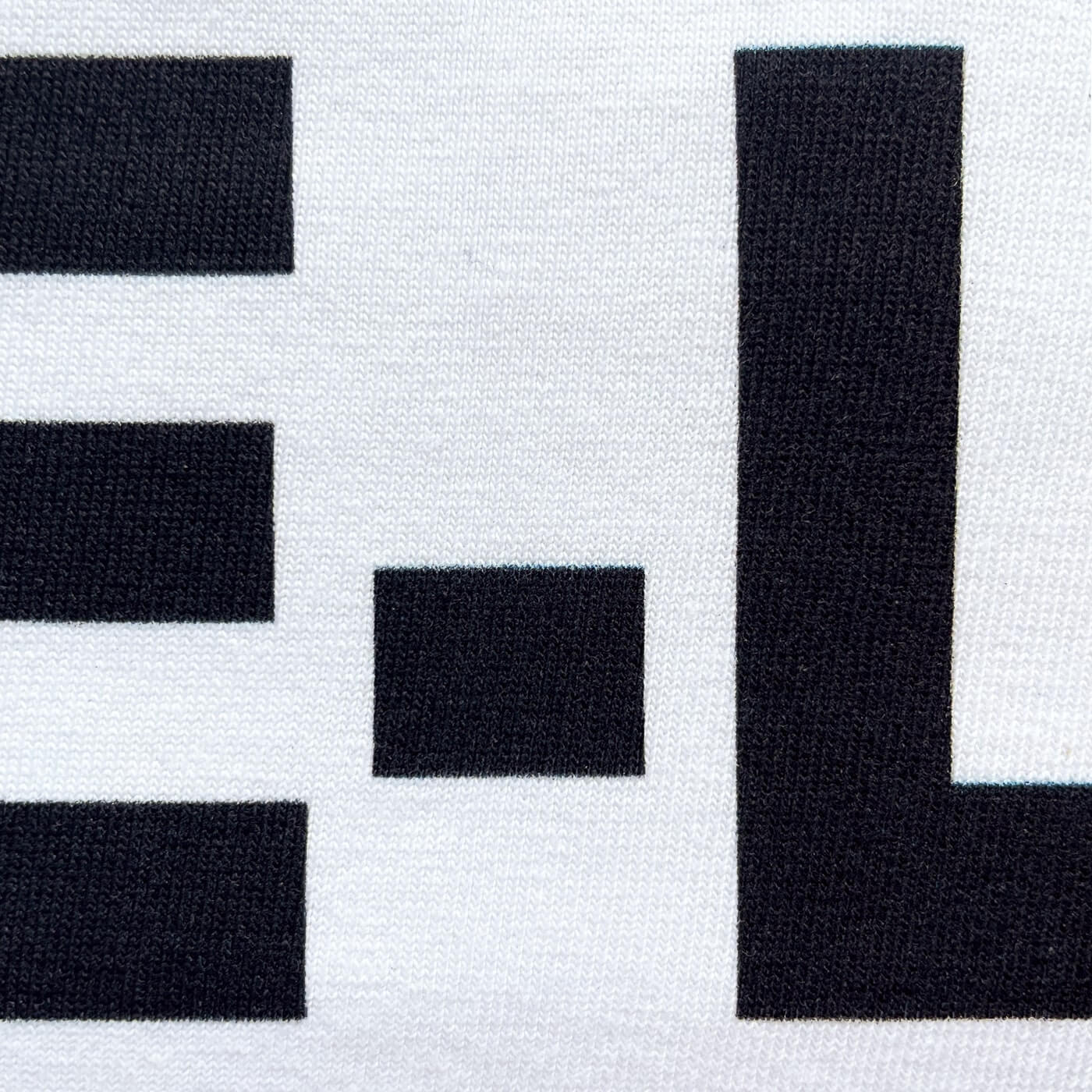 CALMECS T-SHIRT IN COLOR WHITE WITH BLACK LIFE-LIFE BALANCE FONT FRONT PRINT. CLOSE UP LETTER E-L.