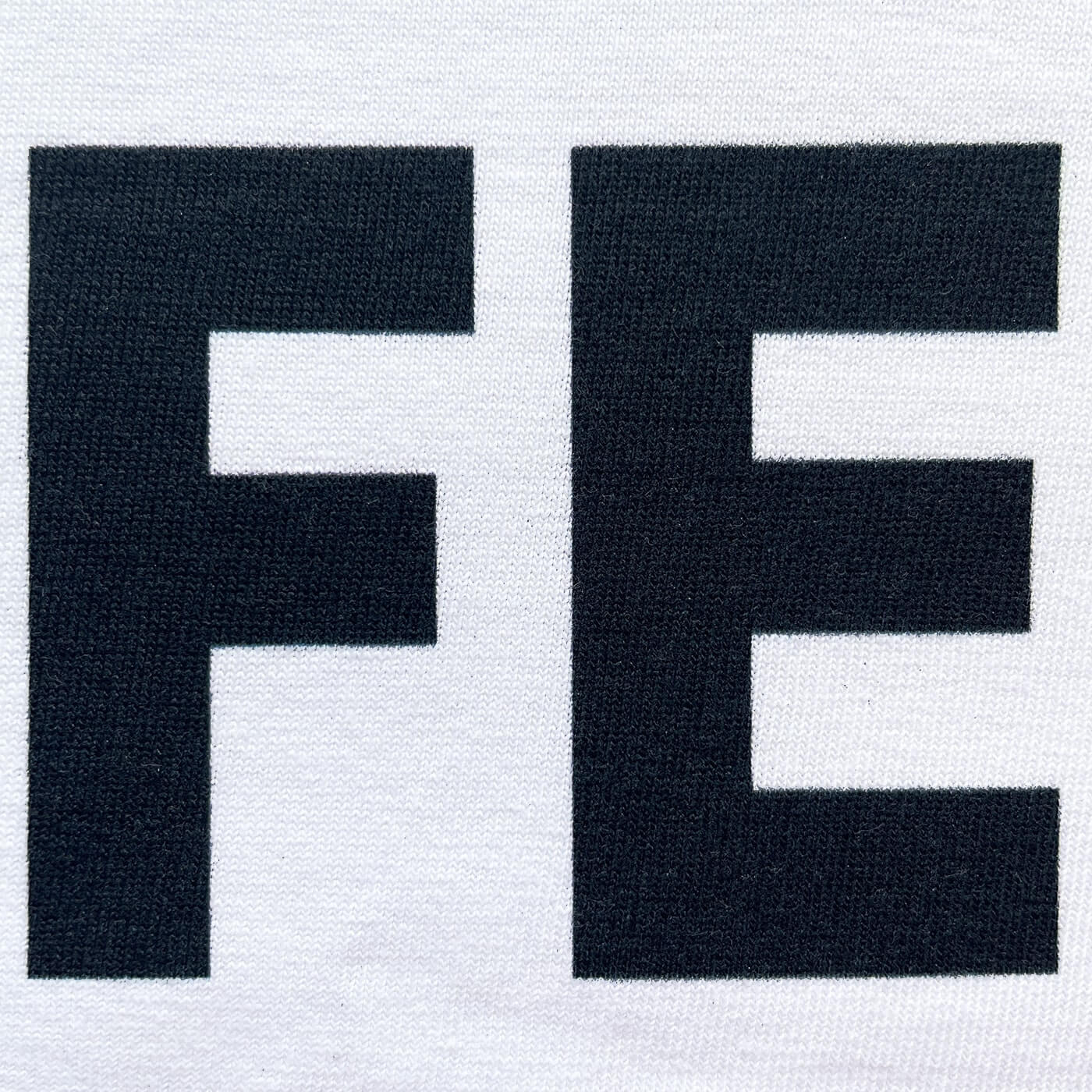 CALMECS T-SHIRT IN COLOR WHITE WITH BLACK LIFE-LIFE BALANCE FONT FRONT PRINT. CLOSE UP LETTERS F AND E.