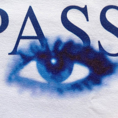 CALMECS T-SHIRT IN COLOR WHITE WITH BLUE TUTTO PASSA FONT AND BLUE EYES FRONT PRINT. CLOSE UP RIGHT EYE.