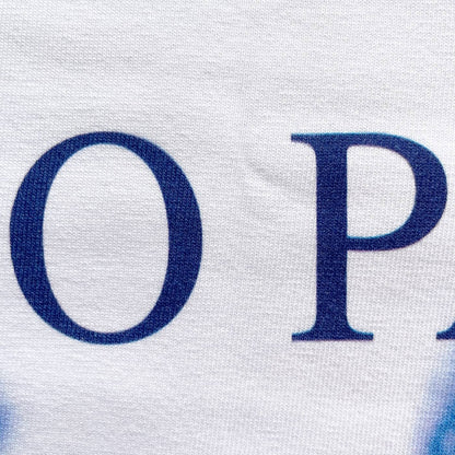 CALMECS T-SHIRT IN COLOR WHITE WITH BLUE TUTTO PASSA FONT AND BLUE EYES FRONT PRINT. CLOSE UP O P.