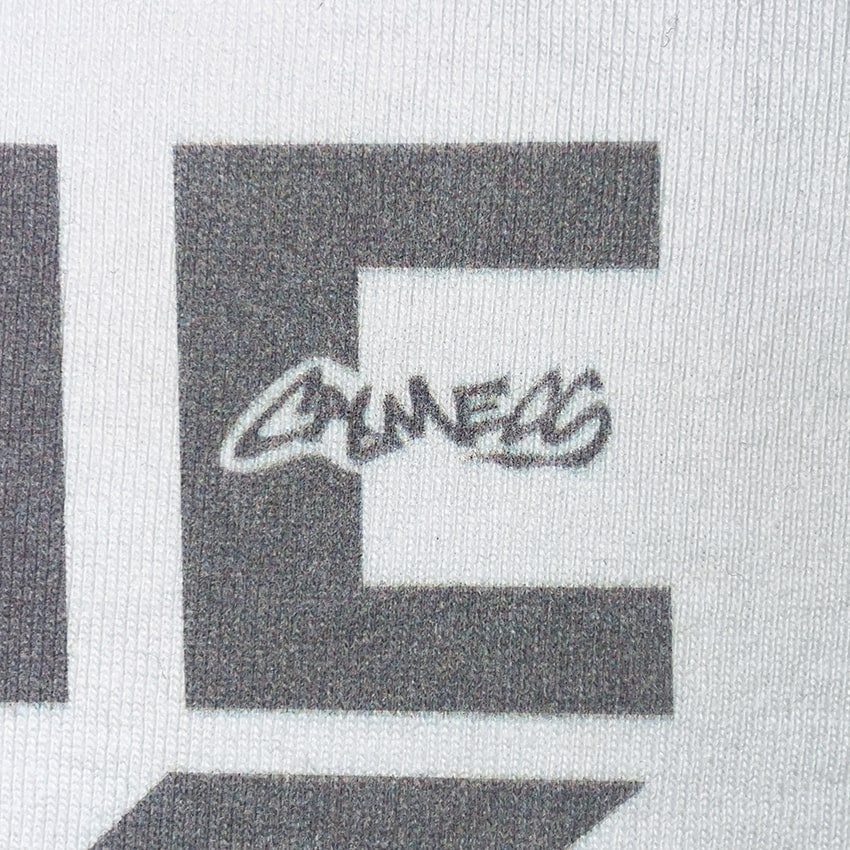 CALMECS T-SHIRT IN COLOR WHITE WITH GREY FONT FRONT PRINT. CALMECS LOGO CLOSE UP.